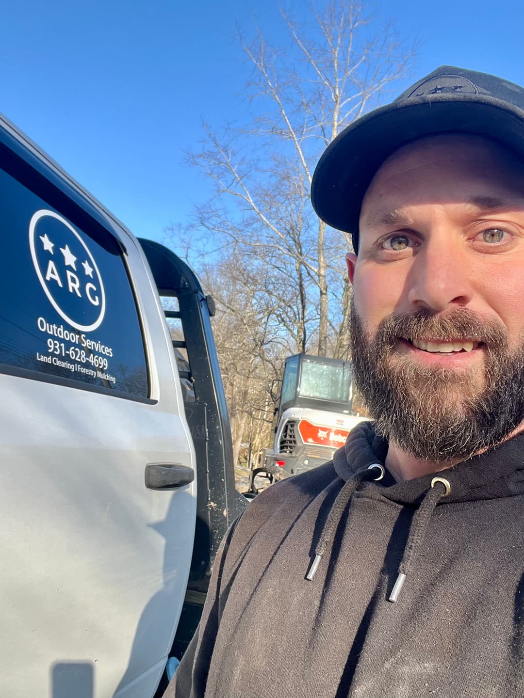 Man smiling next to a truck with ARC Outdoor Services logo, land clearing and forestry expert.